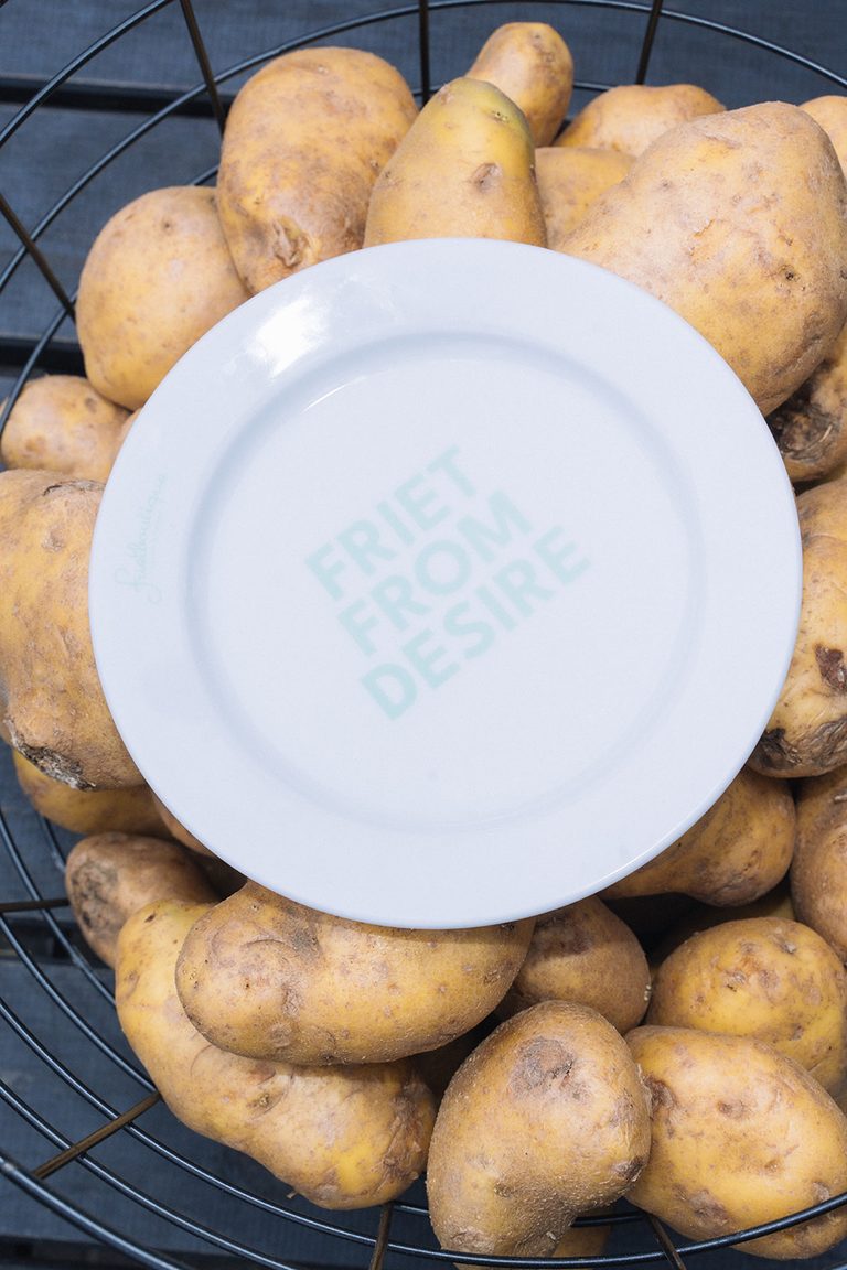 Een bord van Frietboutique op een berg aardappels